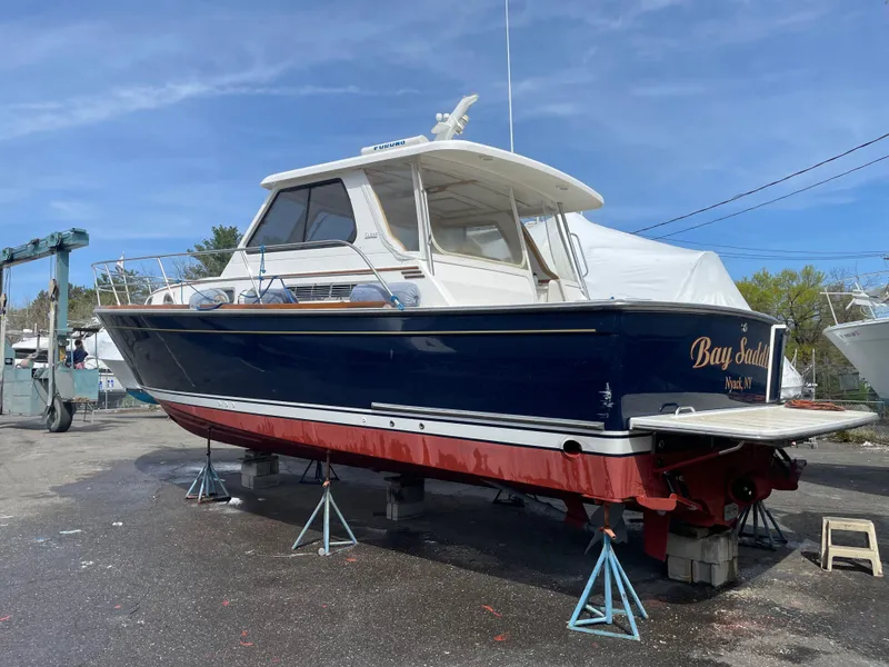 Slide: The Image of 2005 Sabre 38 Hardtop Express boat on stands, blue hull, red bottom, outdoor setting. - 8