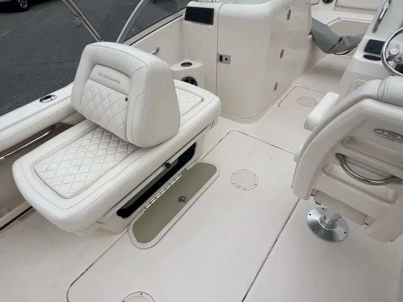 Slide: The Image of 2021 Grady-White Freedom 215 boat interior with white cushioned seating and steering area. - 15