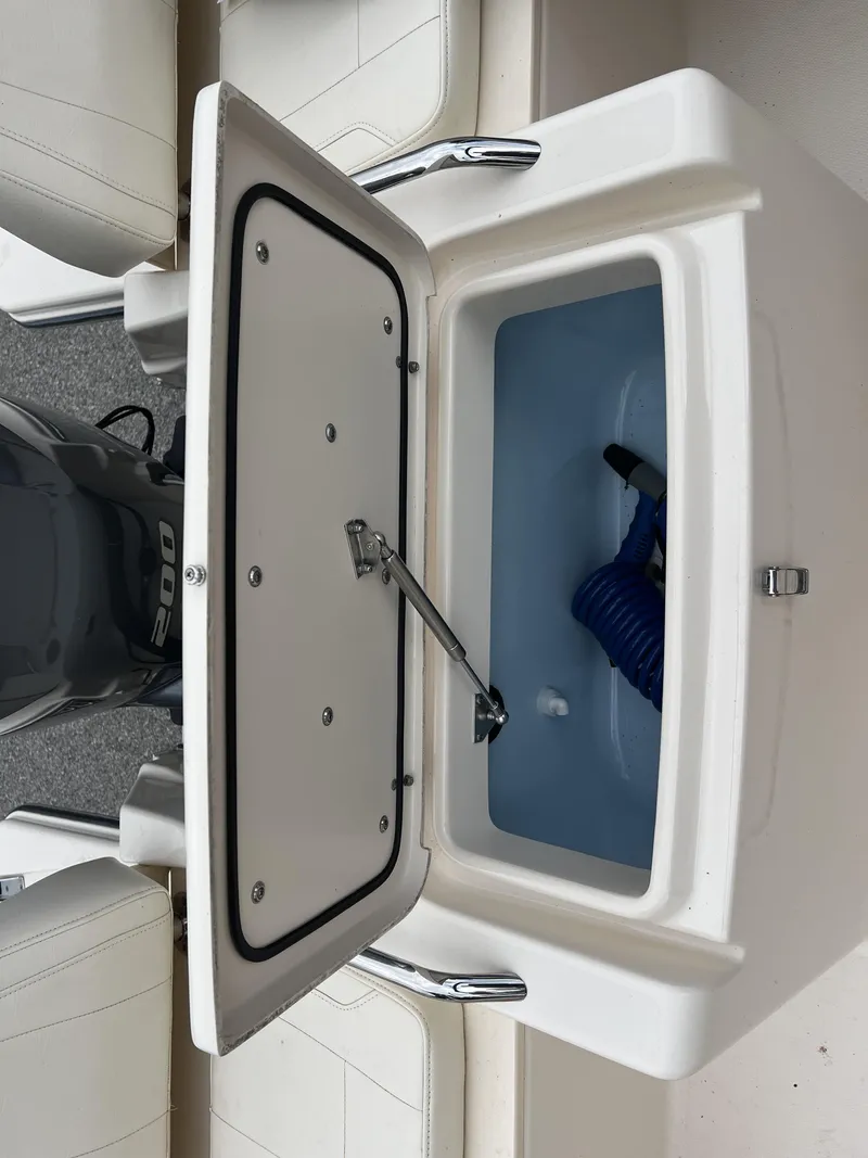 Slide: The Image of Open storage compartment on 2021 Grady-White Freedom 215 boat, featuring a blue coiled hose. - 8