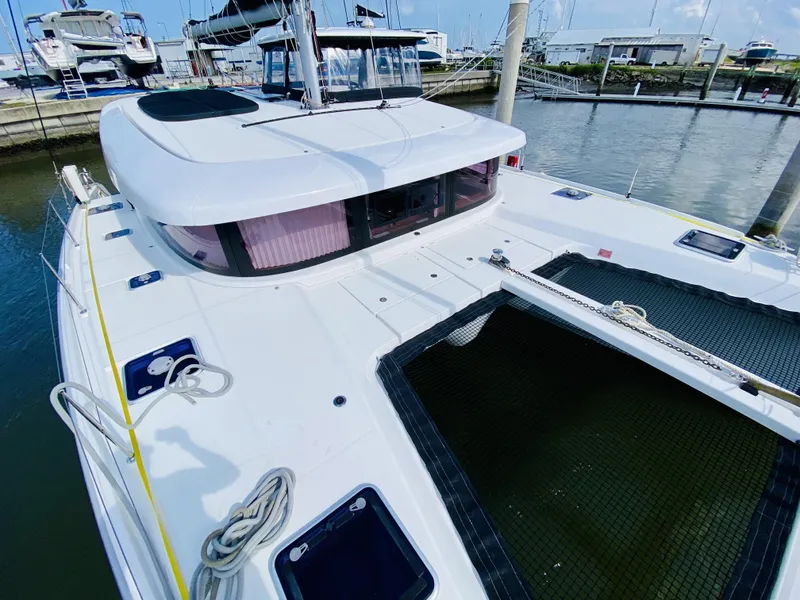 Slide: The Image of 2019 Lagoon 42 Owners Version catamaran docked at marina, showcasing sleek design and spacious deck. - 10