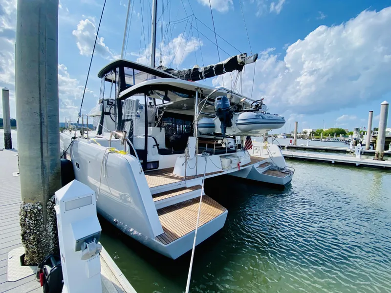 Slide: The Image of 2019 Lagoon 42 Owners Version catamaran docked at marina under blue sky. - 3