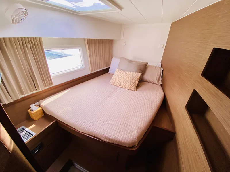 Slide: The Image of 2019 Lagoon 42 Owners Version cabin with cozy bed, window, and wooden interior. - 36