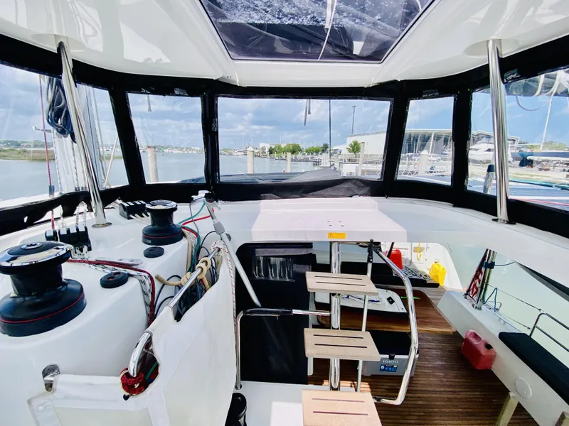 Slide: The Image of Interior view of 2019 Lagoon 42 Owners Version catamaran, featuring helm station and marina backdrop. - 5