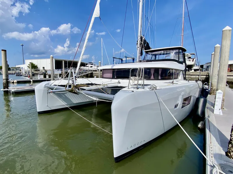 The Image of 2019 Lagoon 42 Owners Version catamaran docked at marina under blue sky. - 0