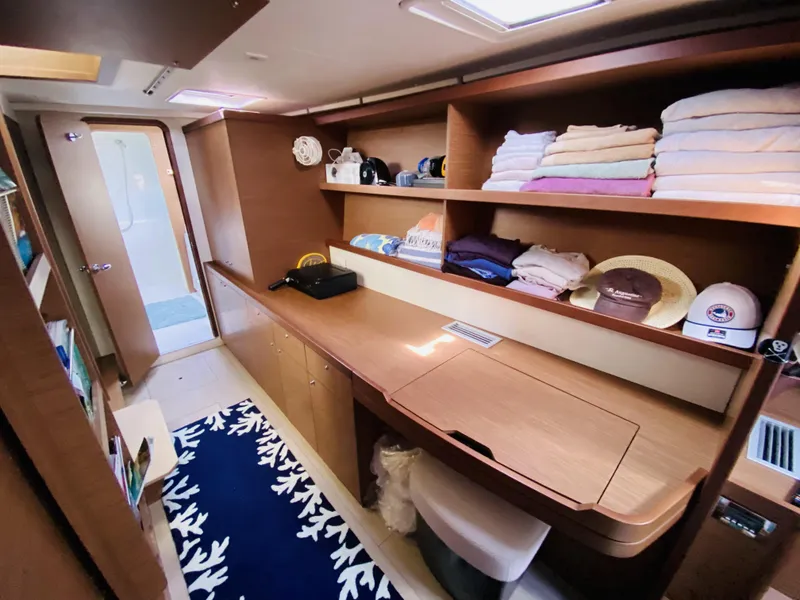 Slide: The Image of 2019 Lagoon 42 Owners Version interior with wooden shelves, desk, and neatly arranged towels. - 25