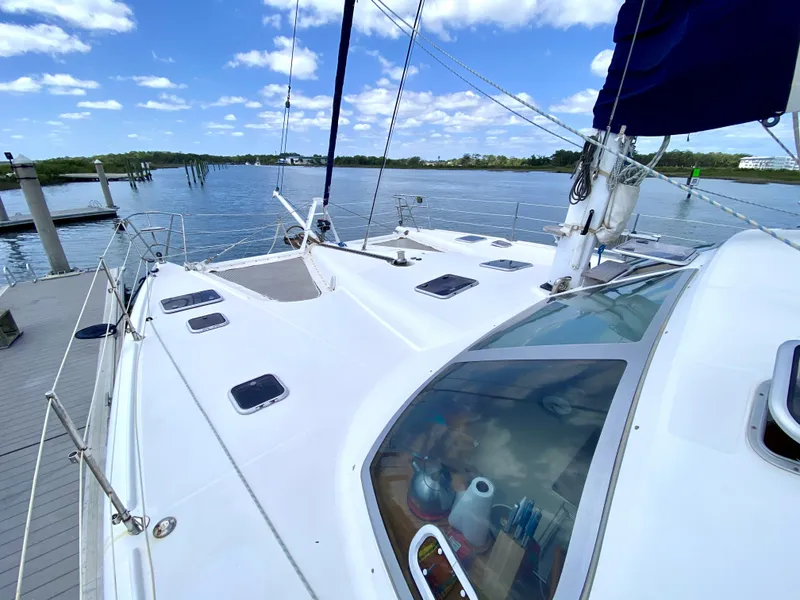 Slide: The Image of Privilege 435 catamaran from 2006 docked by a serene lake under a blue sky. - 8