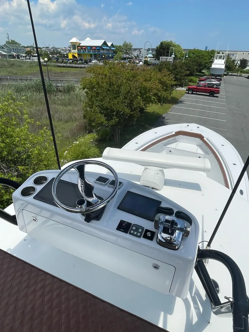 Slide: The Image of 2008 Yellowfin 42 boat helm with steering wheel and controls, docked near greenery and parked cars. - 30