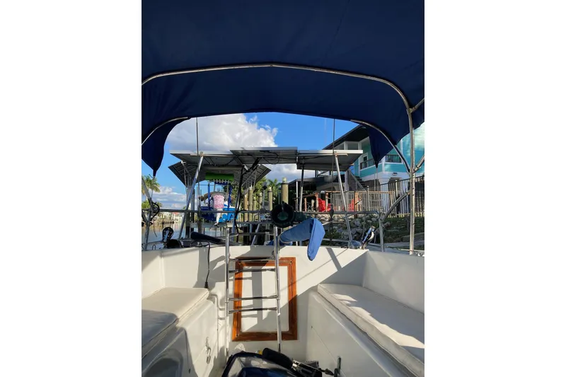 Slide: The Image of 1983 Durbeck 38 sailboat cockpit with blue canopy, docked near waterfront homes. - 26