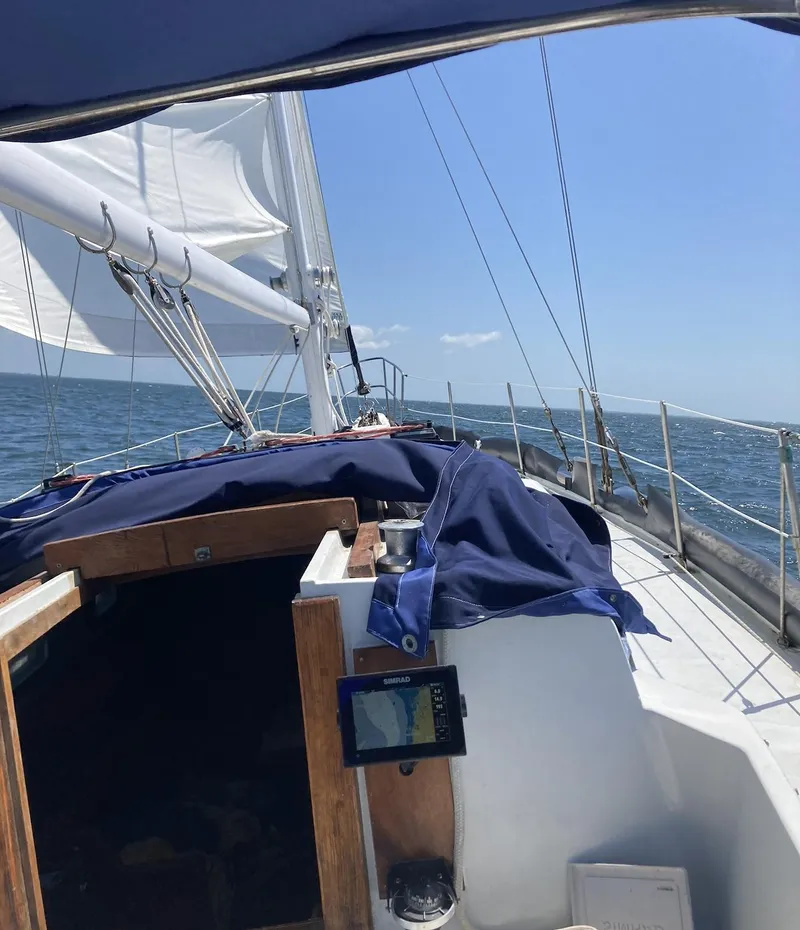 Slide: The Image of Interior of 1983 Durbeck 38 sailboat with blue seating, wooden flooring, and compact kitchen area. - 4