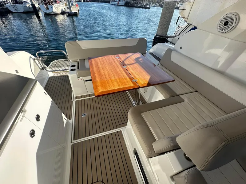 Slide: The Image of 2016 Jeanneau Leader 36 yacht deck with seating and wooden table by the water. - 12