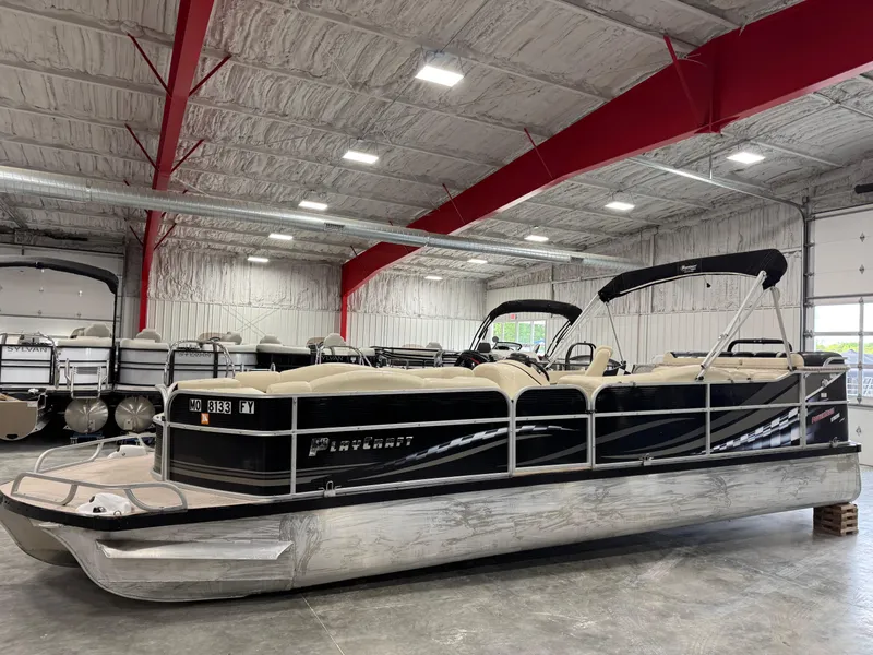 Slide: The Image of 2012 PlayCraft 2700 Extreme pontoon boat in a spacious indoor showroom. - 1