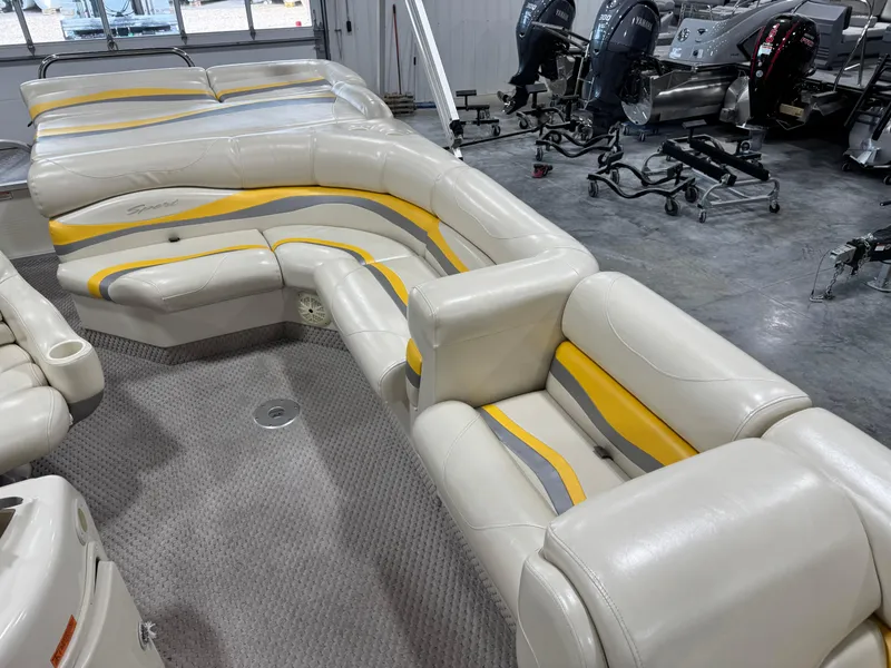 Slide: The Image of 2005 Bennington 2275 RL boat interior with beige and yellow seating in a showroom. - 10