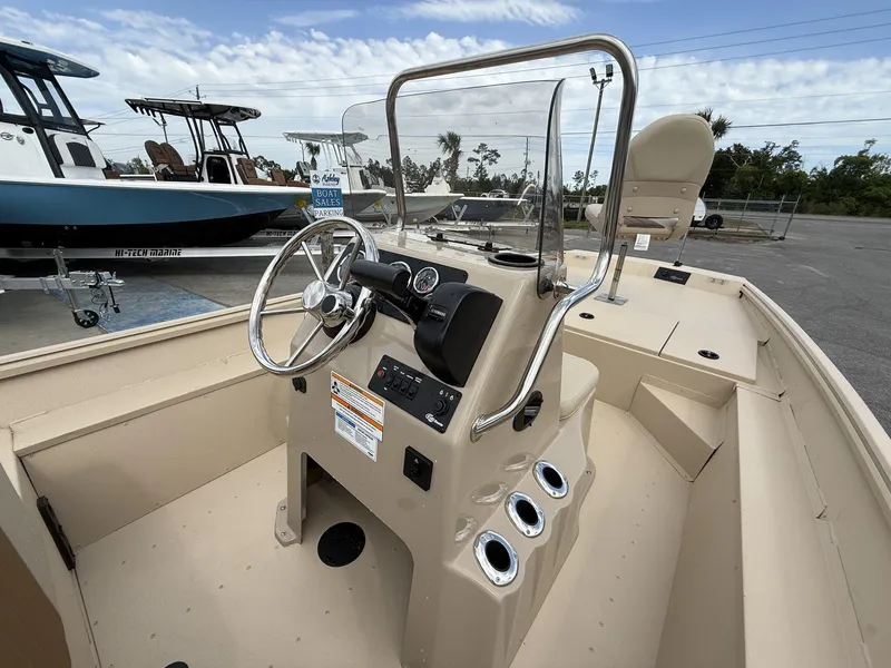 Slide: The Image of 2025 G3 Bay 17 boat interior with steering console and seating, parked at a sales lot. - 5