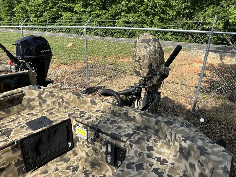 Slide: The Image of Camouflage-patterned Excel Viper F4 1751 boat, 2025 model, with outboard motor, near chain-link fence. - 9
