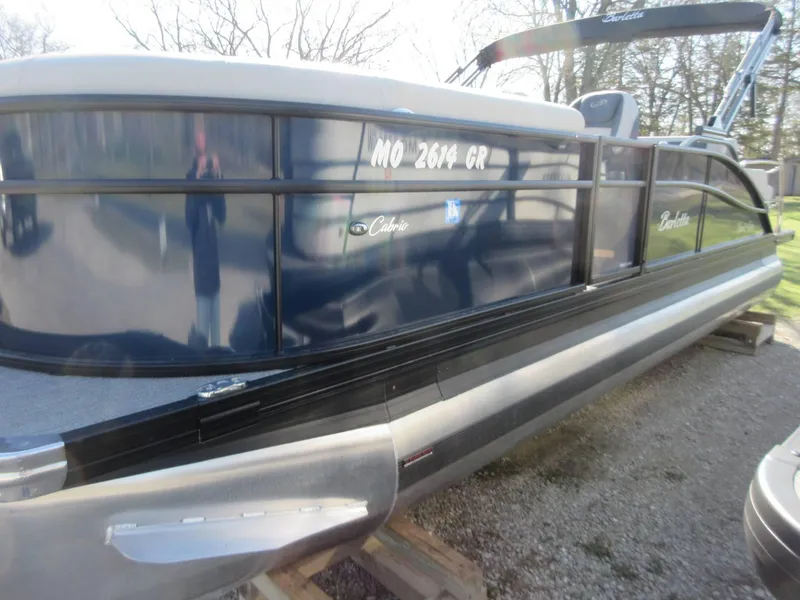Slide: The Image of 2022 Barletta Cabrio 22UC pontoon boat with sleek design, parked on gravel. - 23
