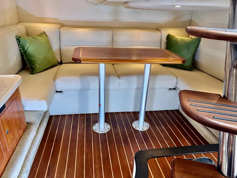 Slide: The Image of 2007 Rinker 350 Express Cruiser interior with wood table, cream seating, and green cushions. - 15