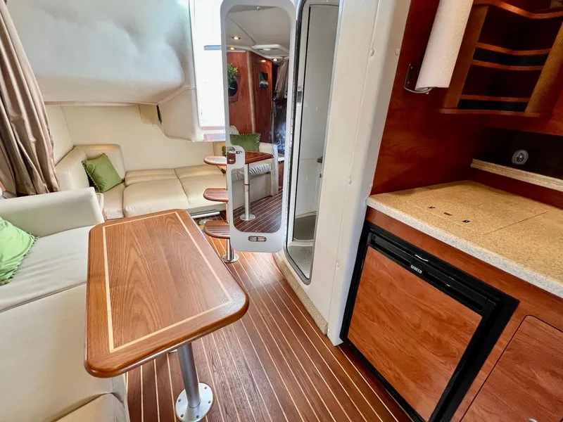 Slide: The Image of 2007 Rinker 350 Express Cruiser interior with wood accents, kitchenette, and seating area. - 16