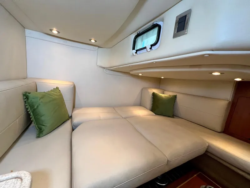 Slide: The Image of 2007 Rinker 350 Express Cruiser cabin with beige seating and green pillows. - 17