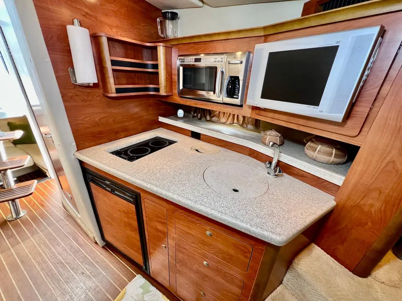 Slide: The Image of 2007 Rinker 350 Express Cruiser kitchen with stove, microwave, and wooden cabinetry. - 18