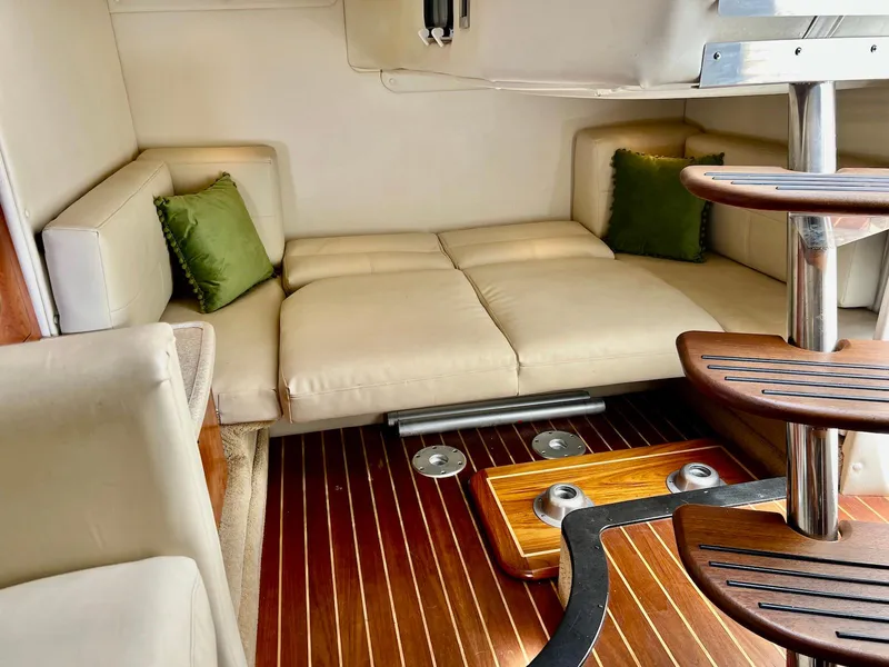 Slide: The Image of 2007 Rinker 350 Express Cruiser interior with beige seating, green cushions, and wooden flooring. - 24