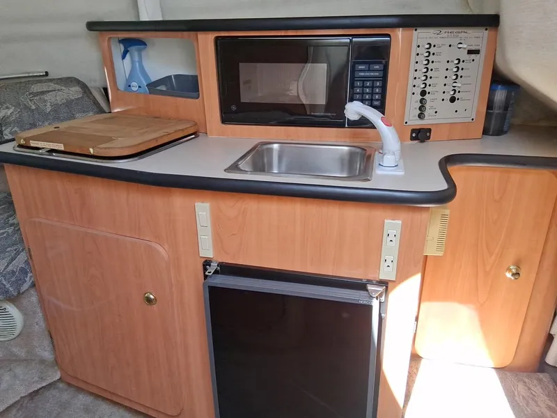 Slide: The Image of 1999 Regal Commodore 242 boat kitchenette with sink, microwave, and mini-fridge. - 12