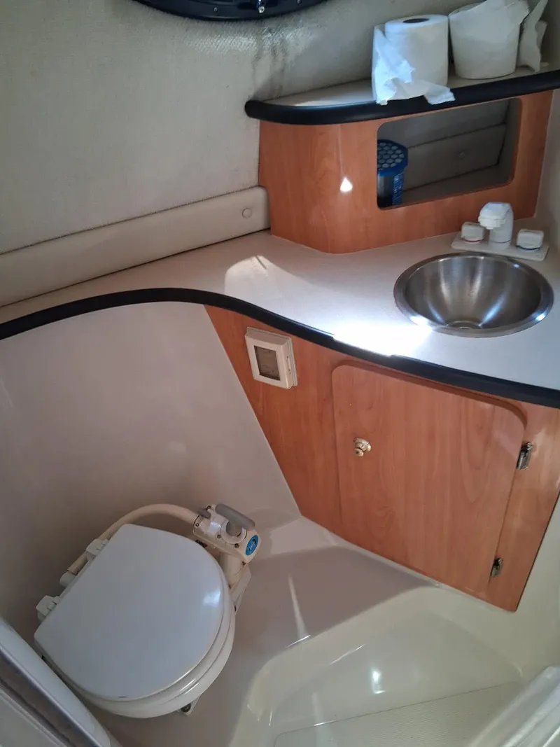 Slide: The Image of 1999 Regal Commodore 242 boat bathroom with sink, toilet, and wooden cabinetry. - 15