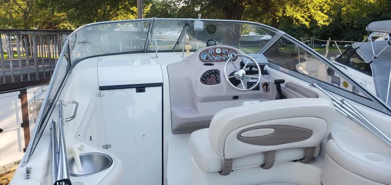Slide: The Image of 1999 Regal Commodore 242 boat interior with steering wheel and seating, docked near trees. - 3