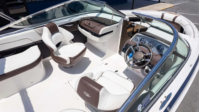 Slide: The Image of 2016 Regal 2300 boat interior with white and brown seating, steering wheel, and dashboard. - 8