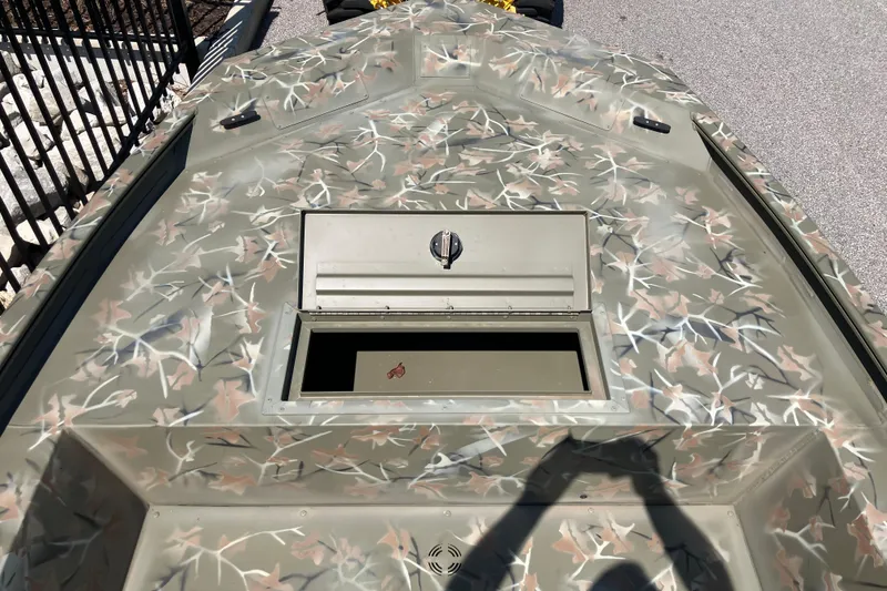 Slide: The Image of 2025 Tracker Grizzly 1754 Jon boat with camouflage pattern and open storage compartment. - 6