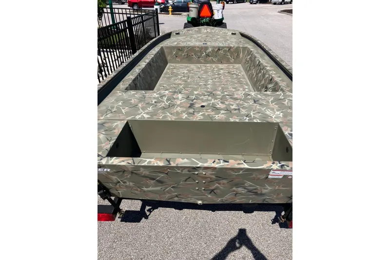 Slide: The Image of 2025 Tracker Grizzly 1754 Jon boat with camouflage design, parked outdoors. - 3