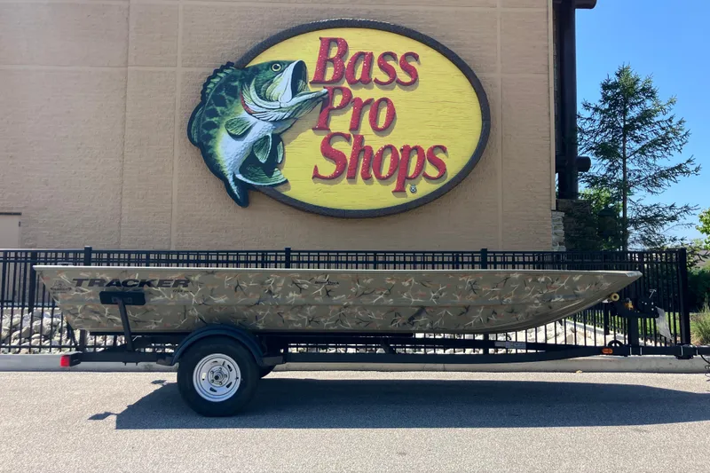 The Image of 2025 Tracker Grizzly 1754 Jon boat outside Bass Pro Shops, featuring camouflage design. - 0