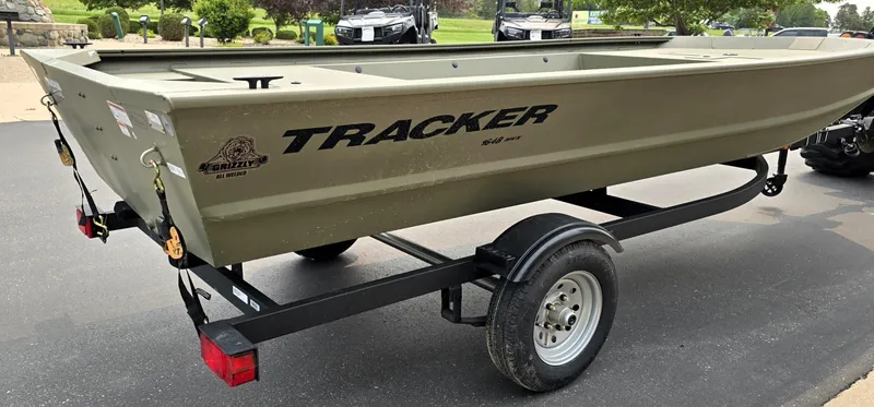 Slide: The Image of 2025 Tracker Grizzly 1648 Jon boat on trailer, parked outdoors. - 2