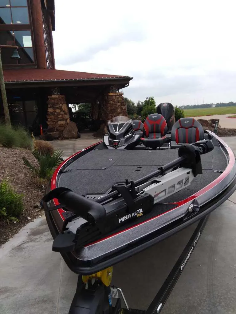 Slide: The Image of 2025 Ranger Z520 boat with Minn Kota motor, parked near a rustic building. - 3