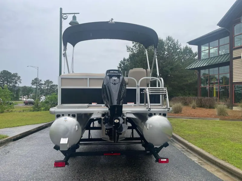 Slide: The Image of 2025 Sun Tracker Party Barge 16 DLX pontoon boat, rear view, parked outdoors. - 4