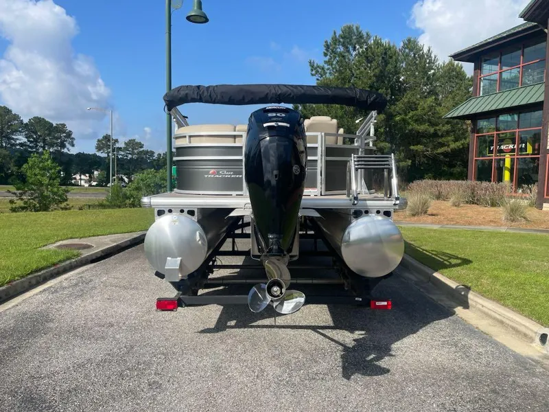Slide: The Image of 2025 Sun Tracker Party Barge 20 DLX pontoon boat, rear view, parked outdoors. - 4