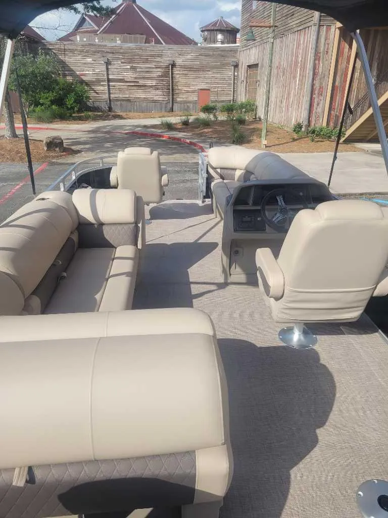 Slide: The Image of 2025 Sun Tracker SportFish 20 DLX pontoon boat interior with beige seating and steering console. - 8