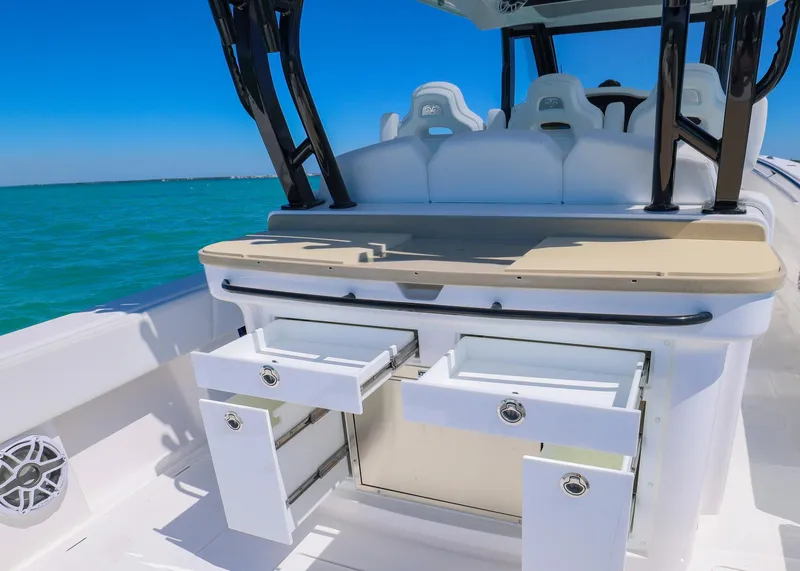 Slide: The Image of 2025 Blackwater 43 Sportfish boat interior with open storage drawers, white seating, and ocean backdrop. - 32