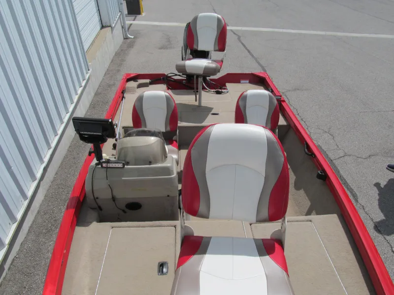 Slide: The Image of 2006 Lowe Stinger 160 boat interior with red and white seats, docked outdoors. - 10