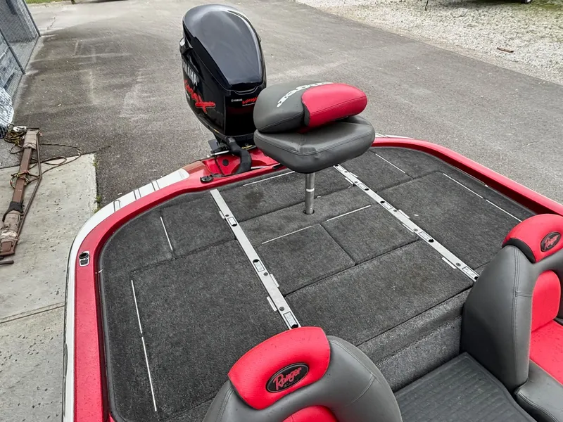 Slide: The Image of 2005 Ranger Z20 Comanche boat with red and black seating and motor, parked on pavement. - 9