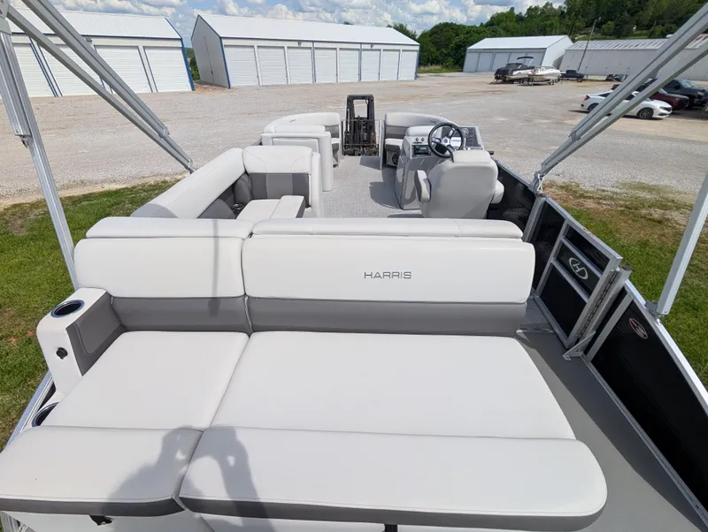 Slide: The Image of 2022 Harris Cruiser 210 pontoon boat with spacious seating, parked near storage units. - 20