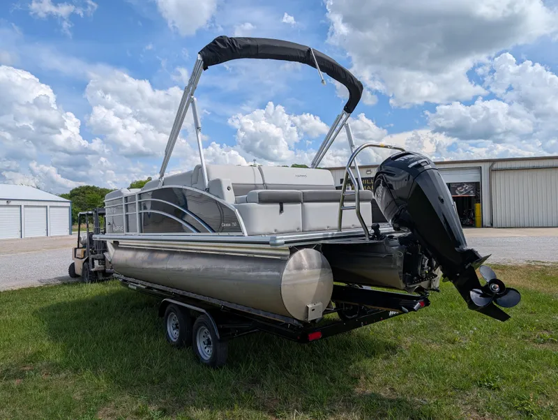 Slide: The Image of 2022 Harris Cruiser 210 pontoon boat on trailer, parked outdoors under cloudy sky. - 5
