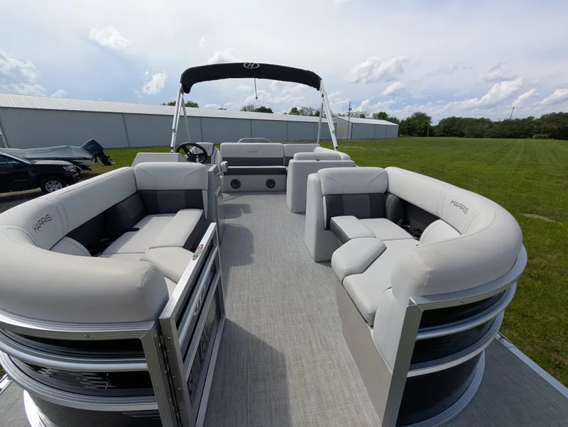 Slide: The Image of 2022 Harris Cruiser 210 pontoon boat with spacious seating and sleek design on grassy area. - 7