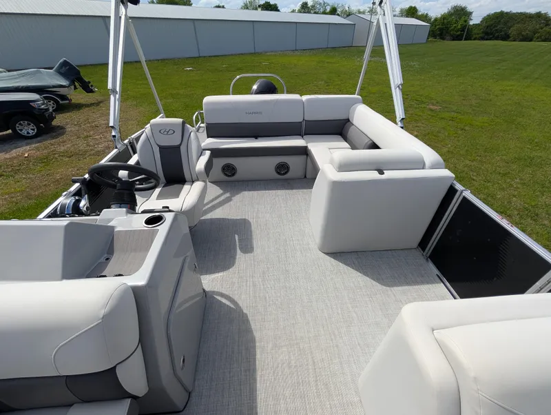 Slide: The Image of 2022 Harris Cruiser 210 pontoon boat with spacious seating and modern design on grassy area. - 8