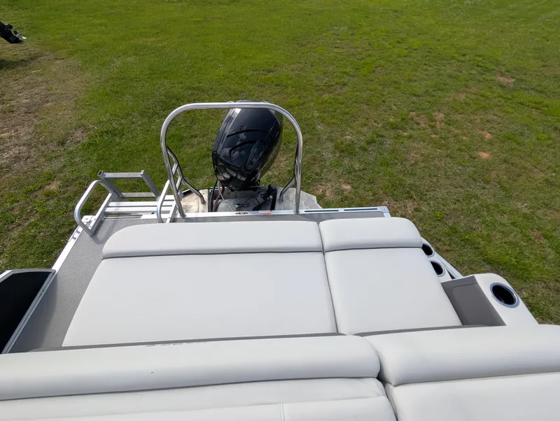 Slide: The Image of 2022 Harris Cruiser 210 boat with outboard motor and cushioned seating, on grassy area. - 9