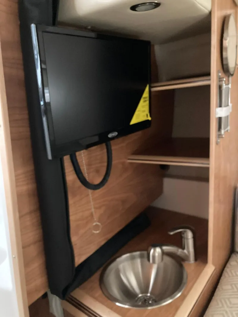 Slide: The Image of 2022 Cutwater C-24 Coupe interior with TV, sink, and wooden shelving. - 21