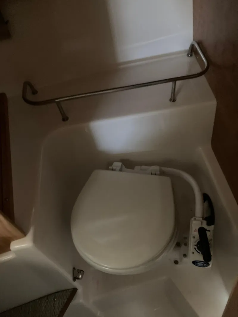 Slide: The Image of 2022 Cutwater C-24 Coupe boat bathroom with compact toilet and safety rail. - 22