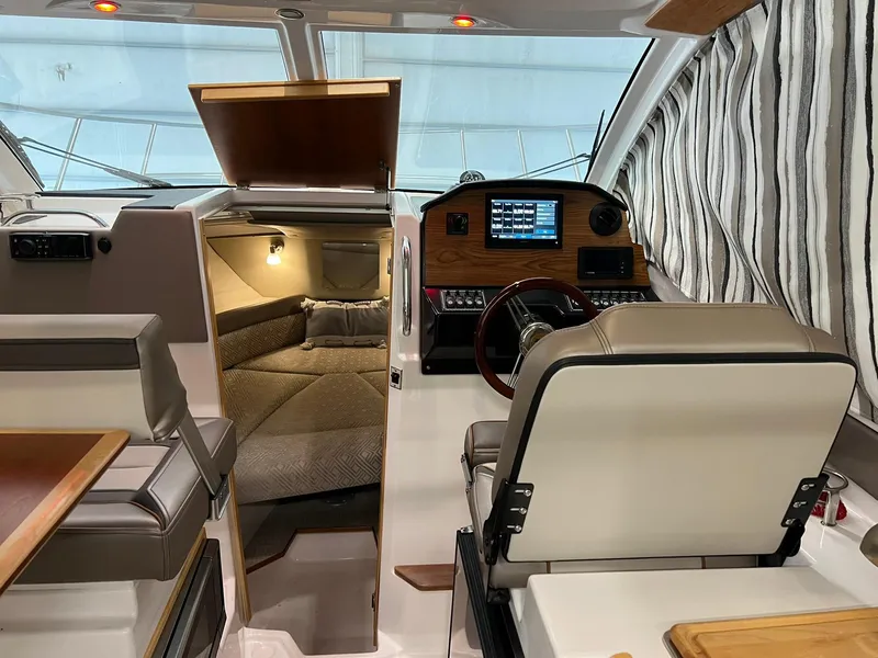 Slide: The Image of 2022 Cutwater C-24 Coupe interior with helm, seating, and cabin view. - 25