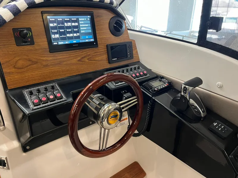 Slide: The Image of 2022 Cutwater C-24 Coupe helm with wood accents, digital display, and steering wheel. - 9