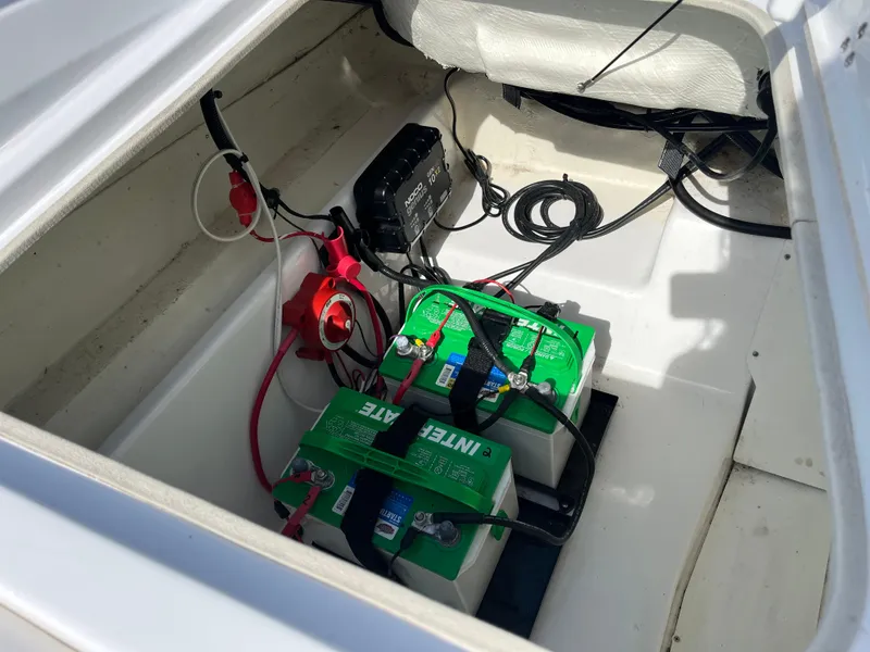 Slide: The Image of 2023 Tahoe 185 S boat battery compartment with dual green batteries and wiring. - 17