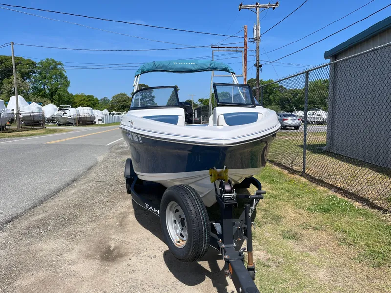 Slide: The Image of 2023 Tahoe 185 S boat on trailer, parked roadside under clear blue sky. - 21